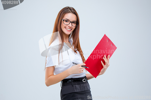 Image of The smiling young business woman with pen and tablet for notes on gray background