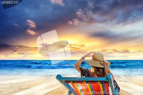 Image of Woman in chaise-lounge relaxing at sunset 