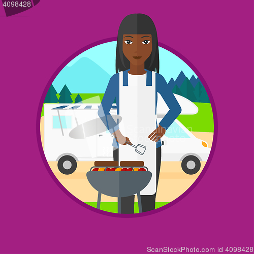 Image of Woman having barbecue in front of camper van.