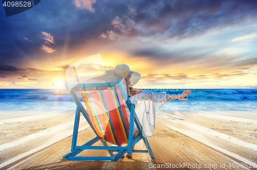 Image of Woman in chaise-lounge relaxing at sunset 
