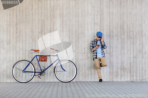 Image of hipster man in earphones with smartphone and bike