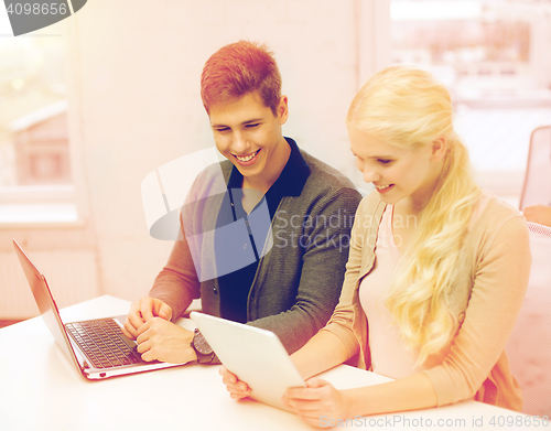 Image of two teens with laptop and tablet pc at school