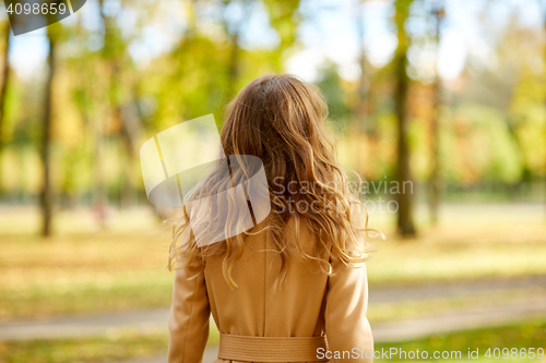 Image of beautiful young woman walking in autumn park