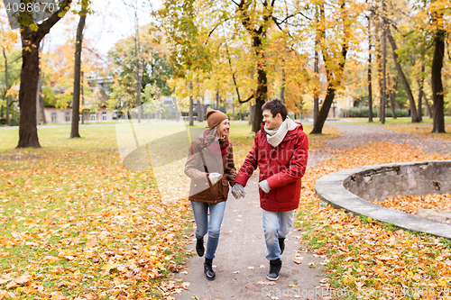 Image of happy young couple running in autumn park