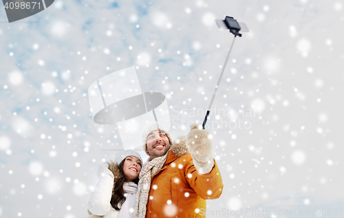 Image of happy couple taking selfie by smartphone in winter