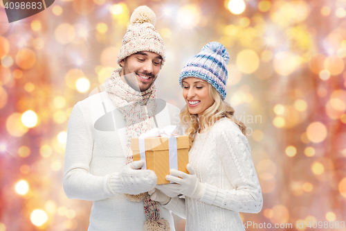 Image of smiling couple in winter clothes with gift box