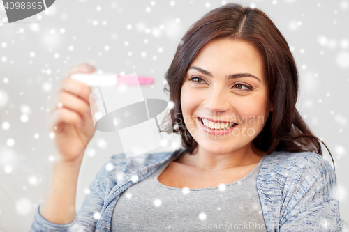 Image of happy woman looking at home pregnancy test