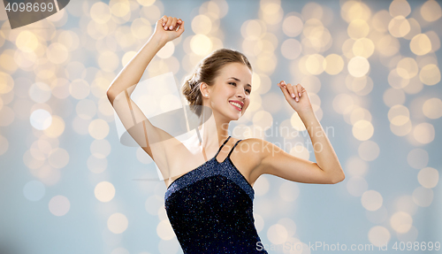 Image of smiling woman dancing with raised hands