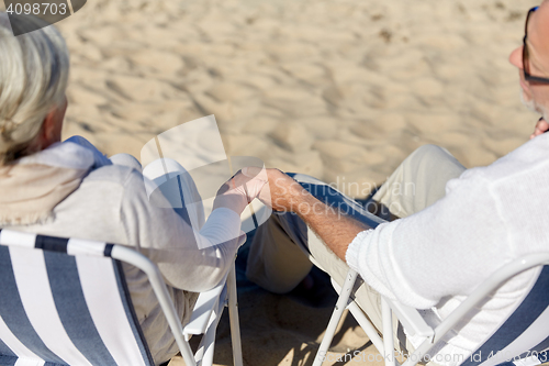 Image of senior couple sitting on chairs at summer beach