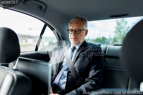 Image of senior businessman driving on car back seat