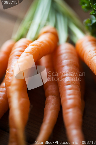 Image of close up of carrot bunch on wooden table