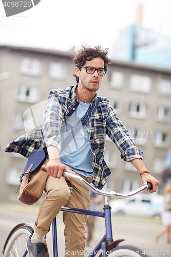 Image of young hipster man with bag riding fixed gear bike