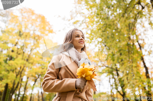 Image of beautiful woman with maple leaves in autumn park