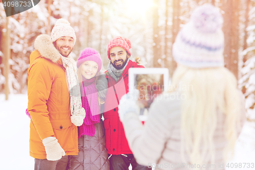 Image of smiling friends with tablet pc in winter forest