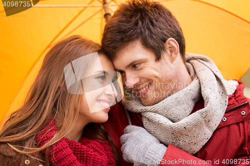 Image of smiling couple with umbrella in autumn park