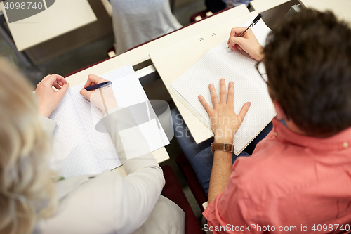 Image of students writing to notebooks at exam or lecture