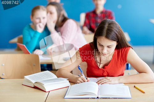 Image of students gossiping behind classmate back at school