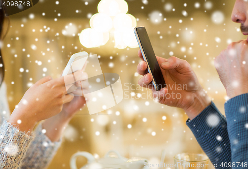 Image of close up of couple with smartphones at cafe
