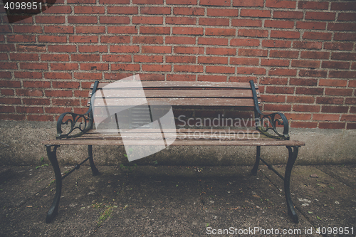 Image of Antique bench at a red brick wall