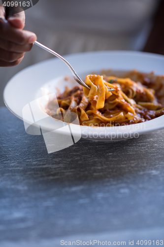 Image of a young African American woman eating pasta