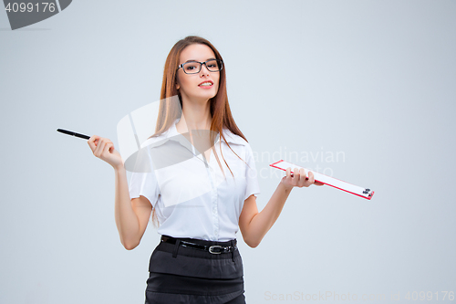 Image of The smiling young business woman with pen and tablet for notes on gray background