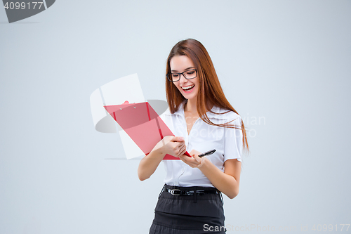 Image of The smiling young business woman with pen and tablet for notes on gray background