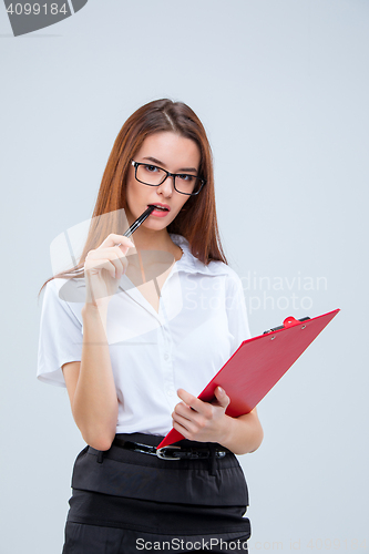 Image of The young business woman with pen and tablet for notes on gray background