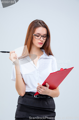 Image of The young business woman with pen and tablet for notes on gray background