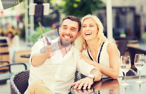 Image of happy couple taking selfie with smartphone at cafe