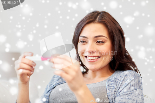 Image of happy woman looking at home pregnancy test