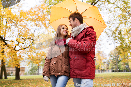 Image of smiling couple with umbrella in autumn park