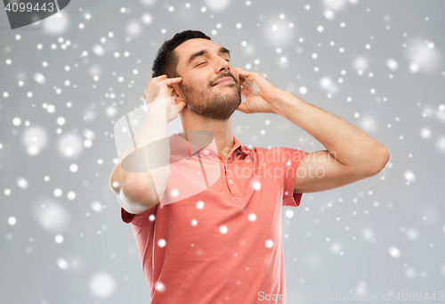 Image of happy man listening to music over snow background