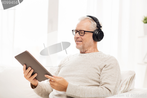 Image of senior man with tablet pc and headphones at home