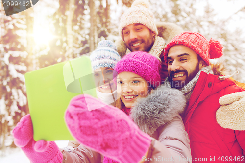 Image of smiling friends with tablet pc in winter forest