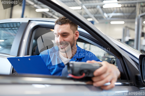 Image of mechanic man with diagnostic scanner at car shop