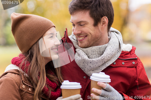 Image of happy couple with coffee walking in autumn park