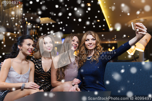 Image of women with smartphone taking selfie at night club