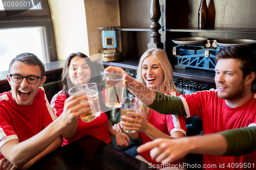 Image of football fans clinking beer glasses at sport bar