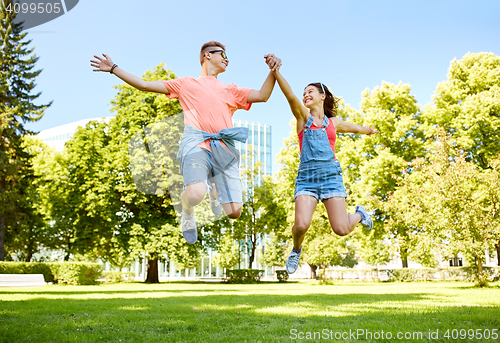 Image of happy teenage couple jumping at summer park