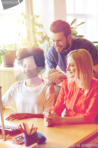 Image of happy creative team with computer in office
