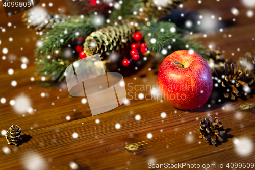 Image of close up of apple with fir decoration on wood