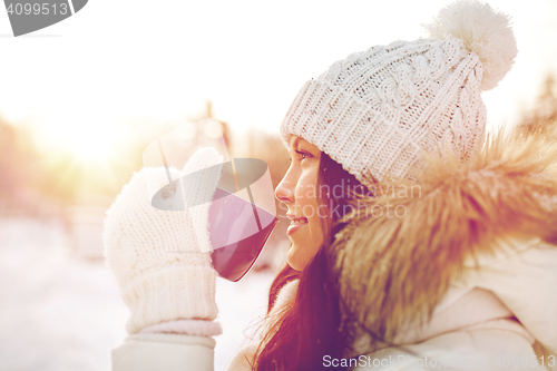 Image of happy young woman with tea cup outdoors in winter