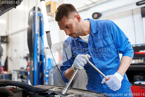 Image of mechanic man with wrench repairing car at workshop