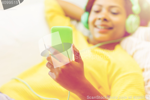 Image of happy african woman with smartphone and headphones