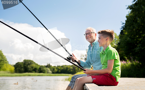 Image of grandfather and grandson fishing on river berth