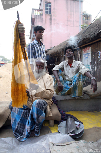 Image of Portrait of a fisherman who weaves a fishing net before the next fishing in Kumrokhali, India