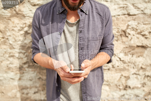 Image of close up of man with smartphone at stone wall