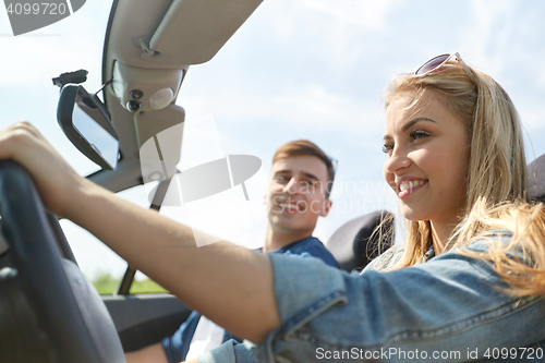 Image of happy couple driving in cabriolet car outdoors