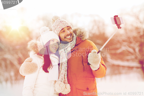 Image of happy couple taking selfie by smartphone in winter