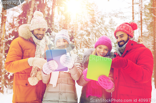 Image of smiling friends with tablet pc in winter forest